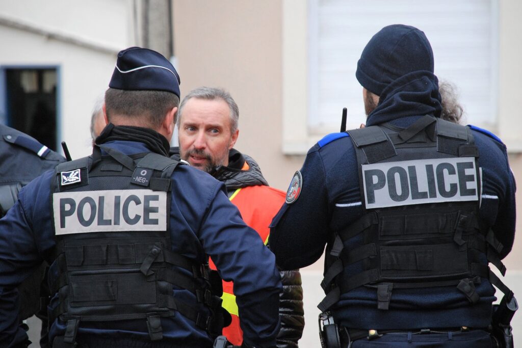 Laurent Indrusiak, avec un gilet orange réfléchissant, fait face à des forces de l’ordre.