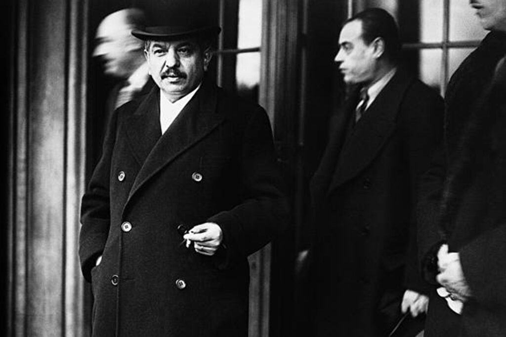 Pierre Laval et un de ses ministres devant une porte de bâtiment.