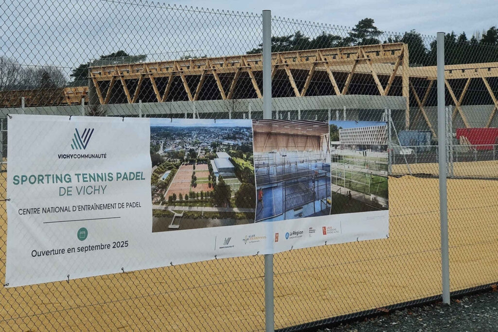 Terrain de tennis et gymnase en construction. Panneau annonçant l’ouverture prochaine du centre national d’entrainement de padel.