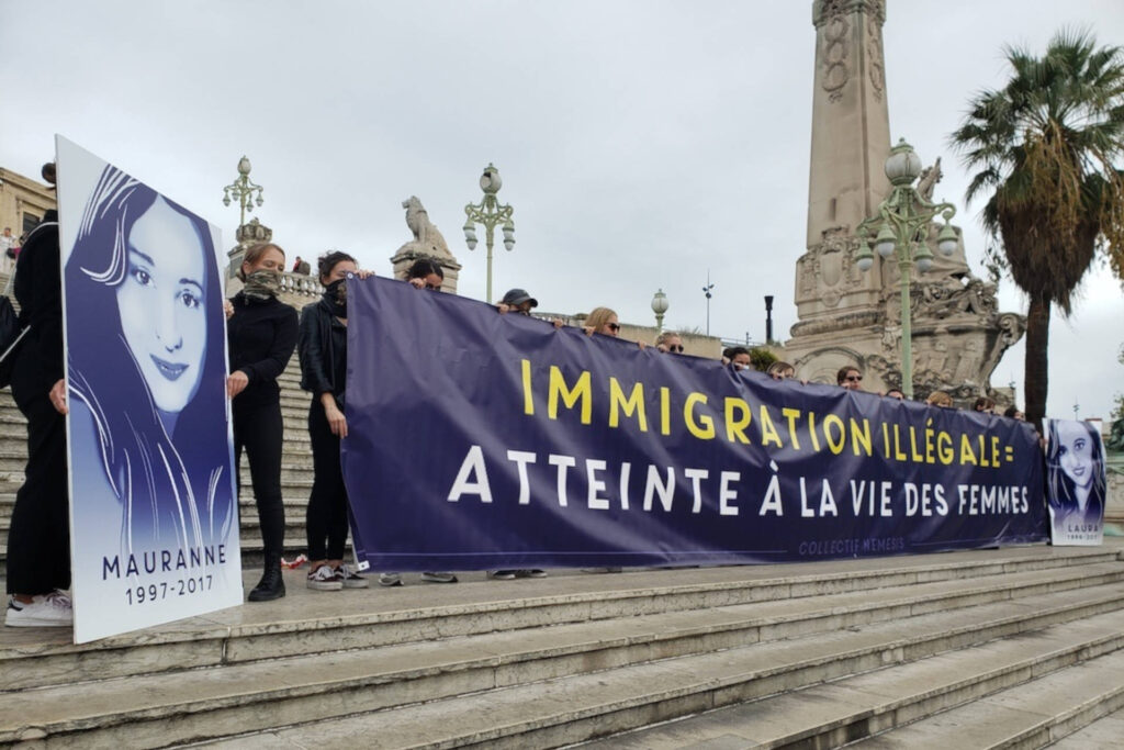 Manifestantes du Collectif Némésis à Marseille qui portent une banderole "immigration illégale: atteinte à la vie des femmes", et des portraits de femmes décédées de féminicides.