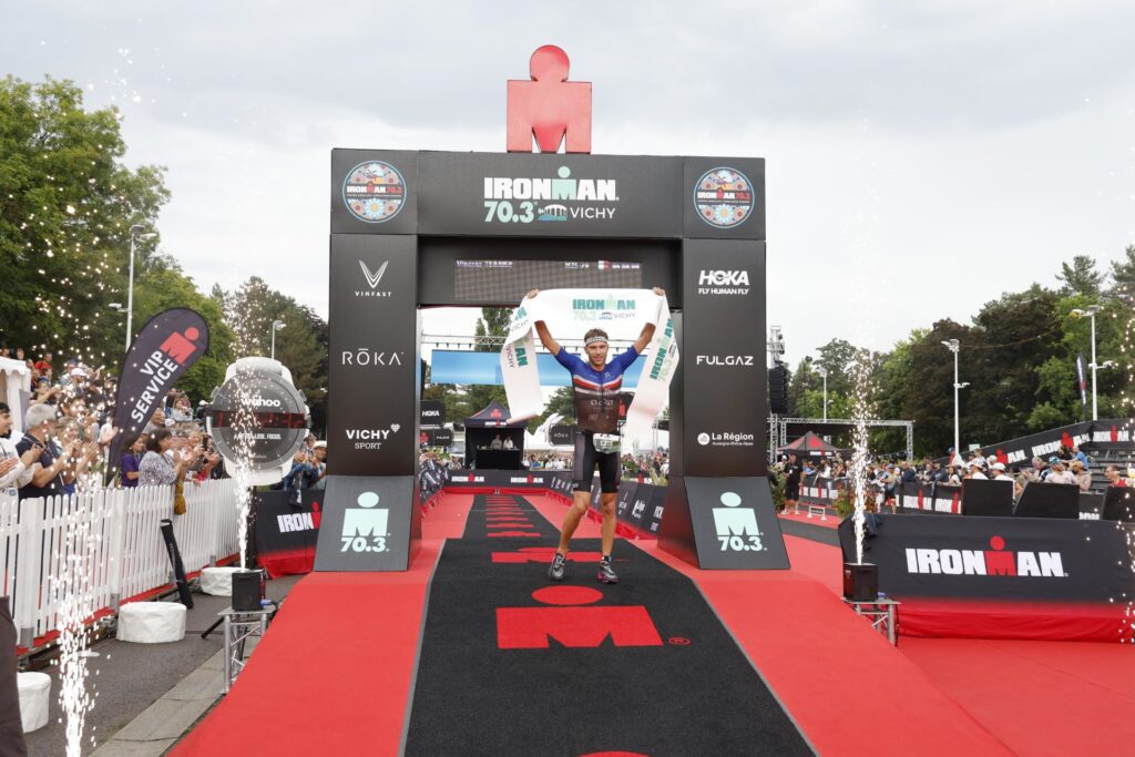 Vincent Terrier, vainqueur de l’Ironman 70.3 levant les bras, après avoir franchi la ligne d’arrivée.