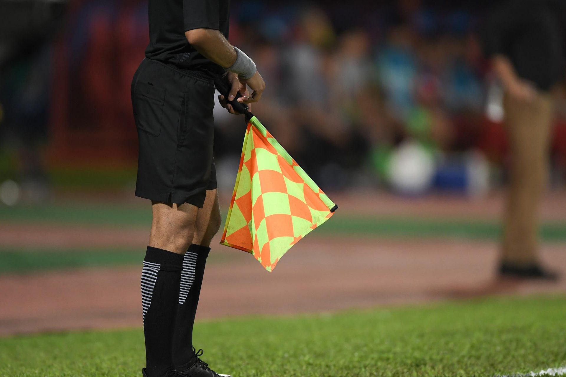 Un arbitre de touche immobile le long du terrain, tenant son drapeau dans la main.