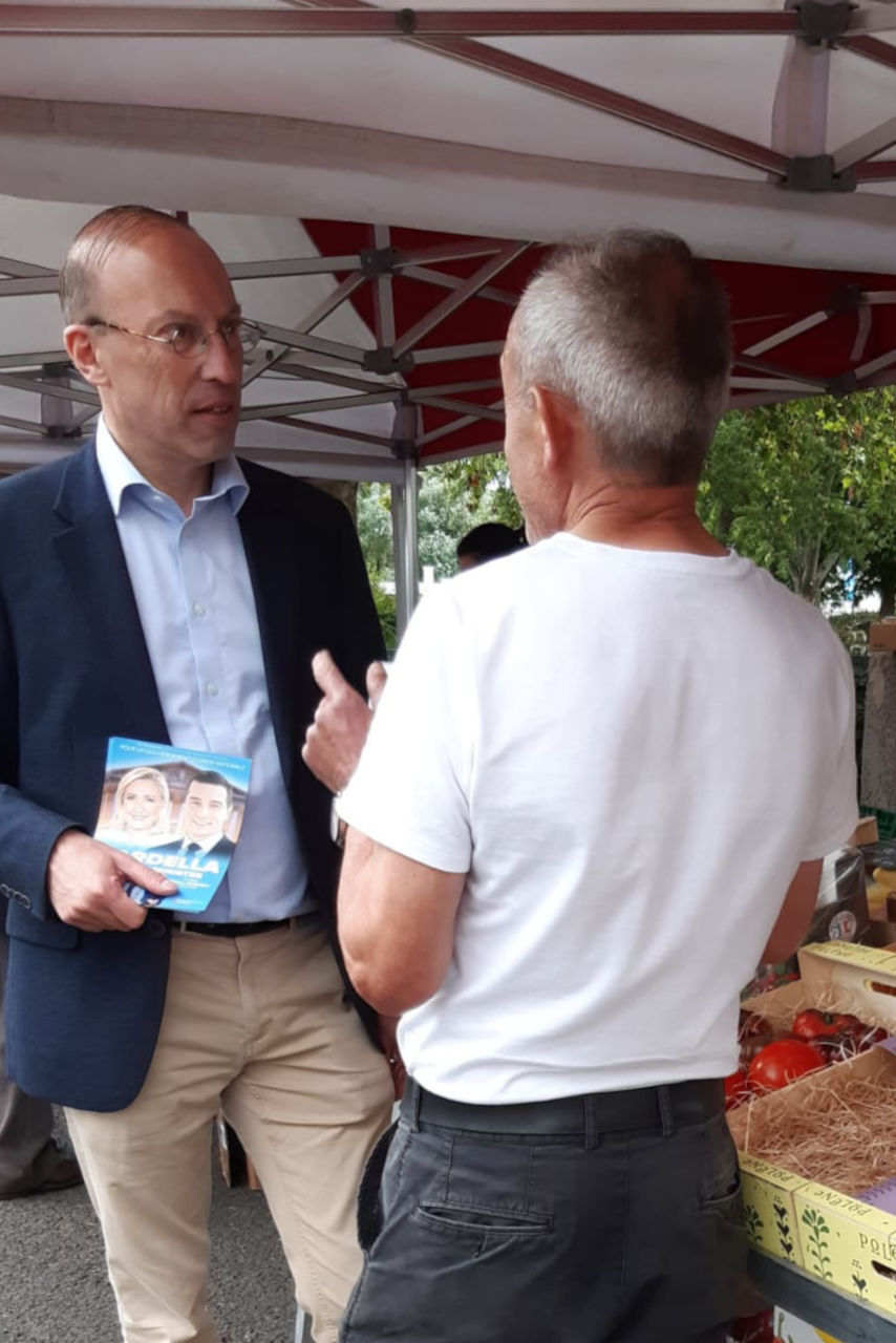 Remy Queney et un passant en discussion dans un marché.