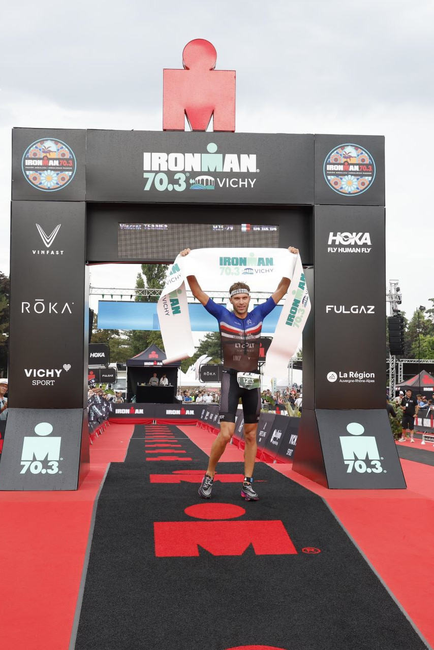 Vincent Terrier, vainqueur de l’Ironman 70.3 levant les bras, après avoir franchi la ligne d’arrivée.